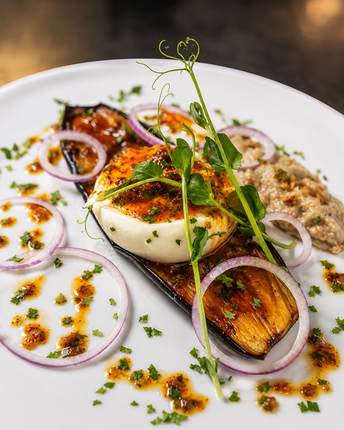 Burrata crémeuse sur aubergine confite, oignons rouges, caviar d'aubergine et huile pimentée
